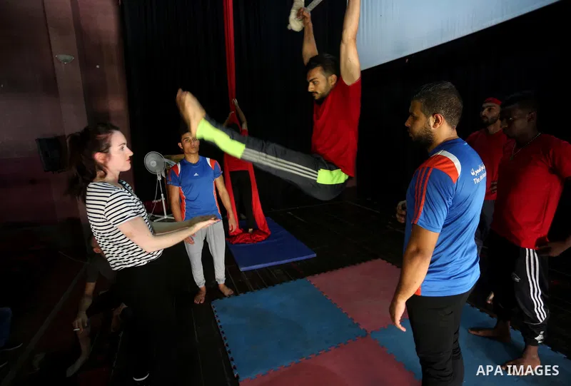 An Irish trainer, Jennifer Higgins, helps a member of Gaza circus to perform during an aerial silks practice class in Gaza City, on August 3, 2017. Photo by Mohammed Asad