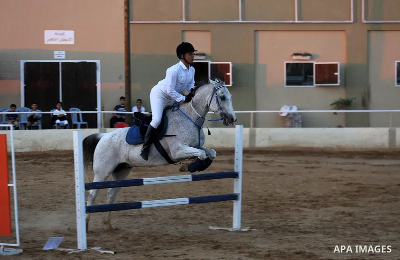 A Palestinian boy rides his horse during a jump obstacles championship, in Gaza city on August 4, 2017. Photo by Mohammed Asad
