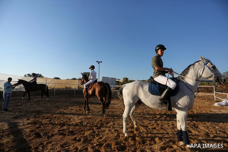 Palestinian boys prepares their horses before a jump obstacles championship, in Gaza city on August 4, 2017. Photo by Mohammed Asad