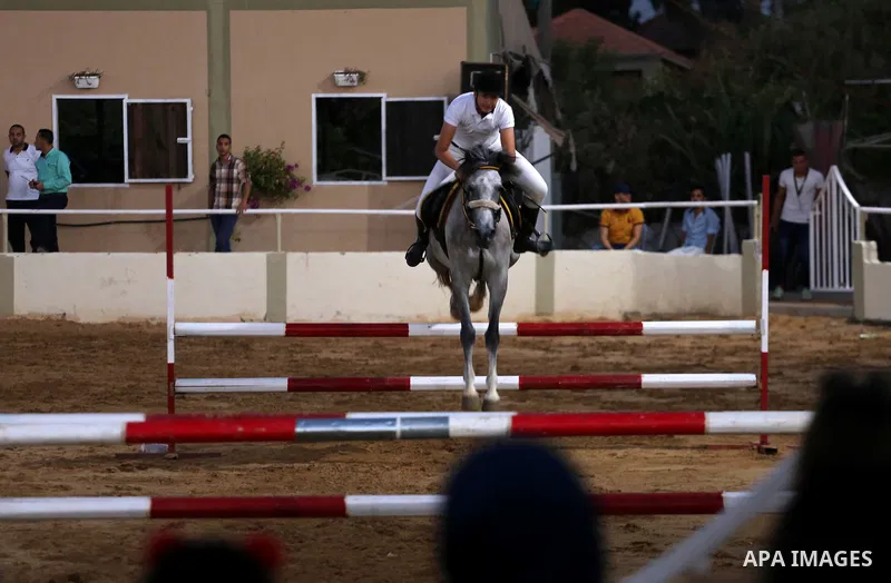 A Palestinian boy rides his horse during a jump obstacles championship, in Gaza city on August 4, 2017. Photo by Mohammed Asad