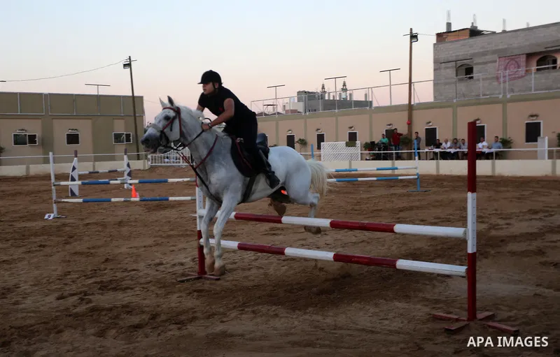 A Palestinian boy rides his horse during a jump obstacles championship, in Gaza city on August 4, 2017. Photo by Mohammed Asad