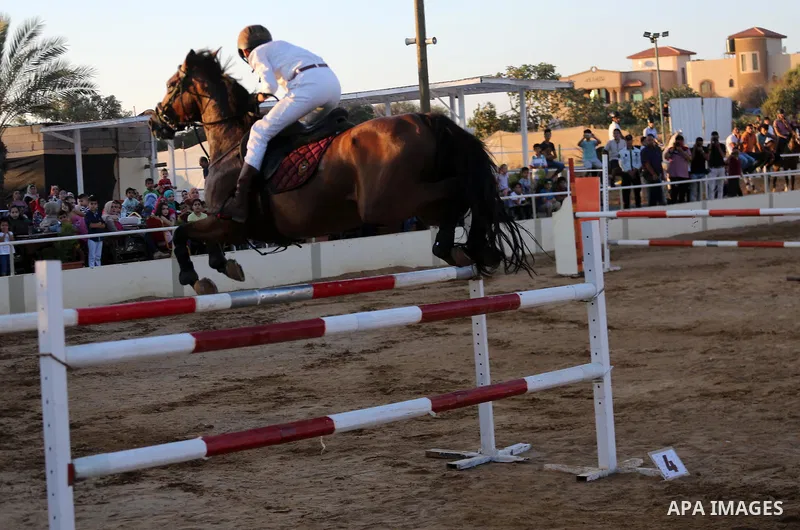A Palestinian boy rides his horse during a jump obstacles championship, in Gaza city on August 4, 2017. Photo by Mohammed Asad