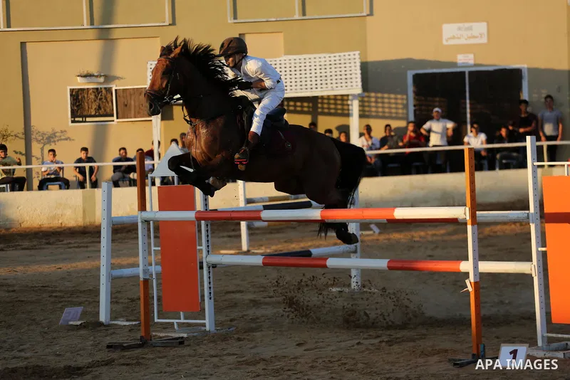 A Palestinian boy rides his horse during a jump obstacles championship, in Gaza city on August 4, 2017. Photo by Mohammed Asad