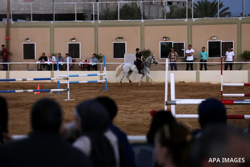 A Palestinian boy rides his horse during a jump obstacles championship, in Gaza city on August 4, 2017. Photo by Mohammed Asad