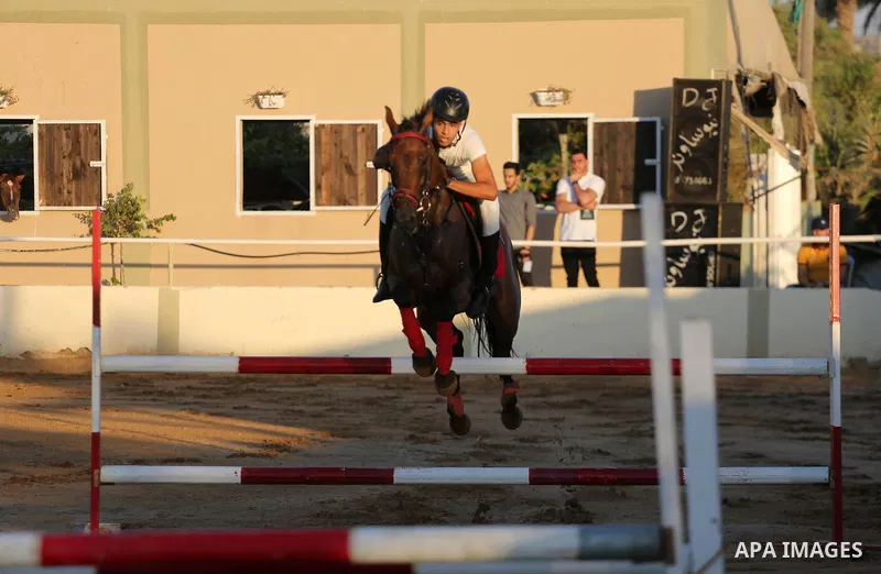 A Palestinian boy rides his horse during a jump obstacles championship, in Gaza city on August 4, 2017. Photo by Mohammed Asad