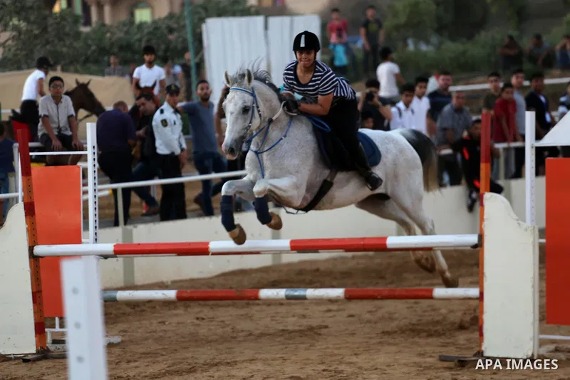 A Palestinian girl rides her horse during a jump obstacles championship, in Gaza city on August 4, 2017. Photo by Mohammed Asad