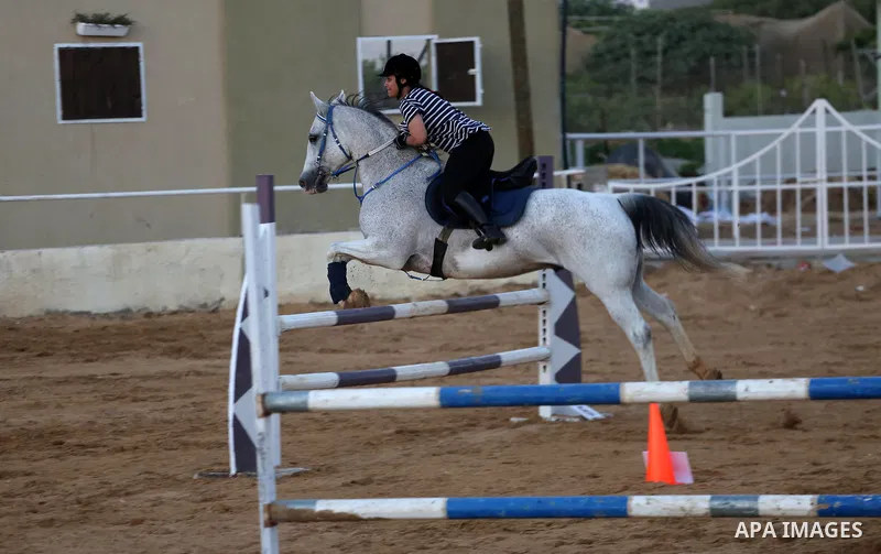 A Palestinian girl rides her horse during a jump obstacles championship, in Gaza city on August 4, 2017. Photo by Mohammed Asad