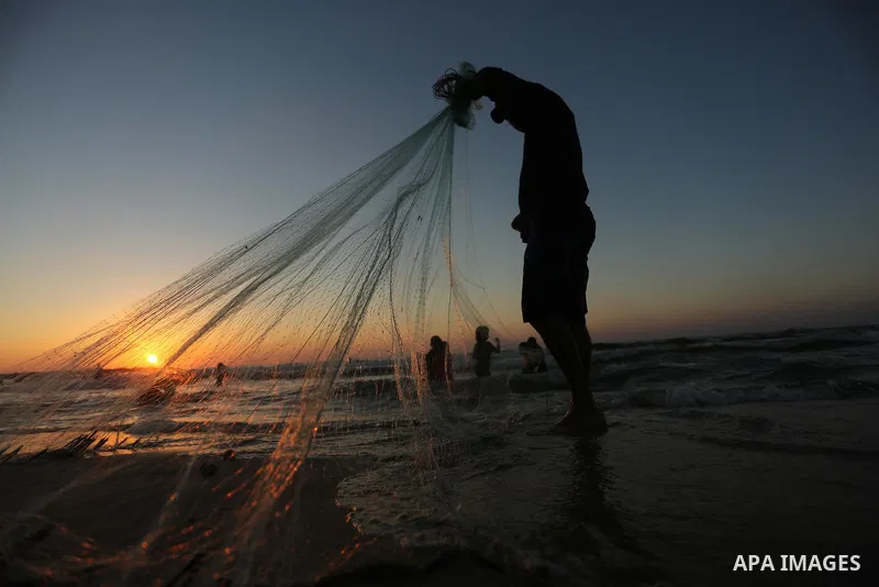 A Palestinian fisherman pulls his nets on a beach in Gaza City on August 4, 2017. Photo by Ashraf Amra