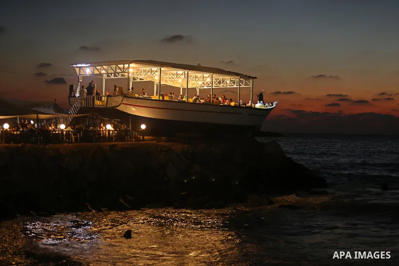 Palestinians are seen aboard "Lolo Rose" ship which has become a popular restaurant, on a beach in Gaza City on August 4, 2017. Photo by Ashraf Amra