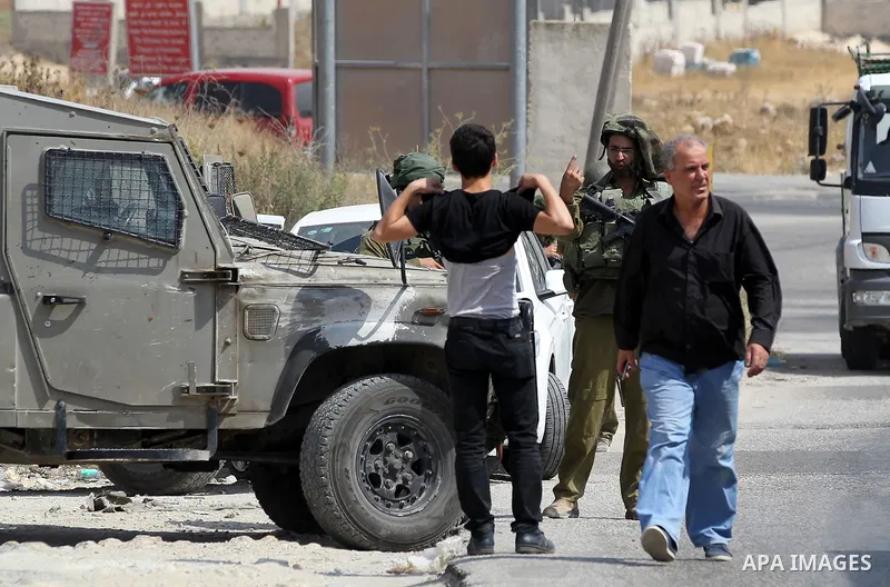 An Israeli soldier searches a Palestinian man at a temporary checkpoint near the West Bank town of Dura, south of Hebron , 24 July 2017. Photo by Wisam Hashlamoun