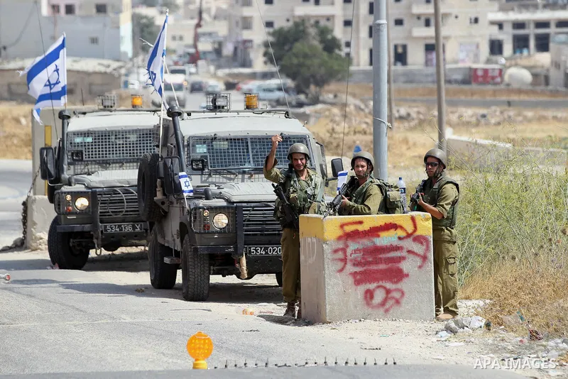 An Israeli soldier searches a Palestinian man at a temporary checkpoint near the West Bank town of Dura, south of Hebron , 24 July 2017. Photo by Wisam Hashlamoun