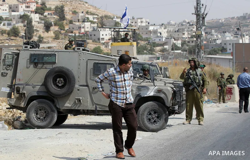 An Israeli soldier searches a Palestinian man at a temporary checkpoint near the West Bank town of Dura, south of Hebron , 24 July 2017. Photo by Wisam Hashlamoun