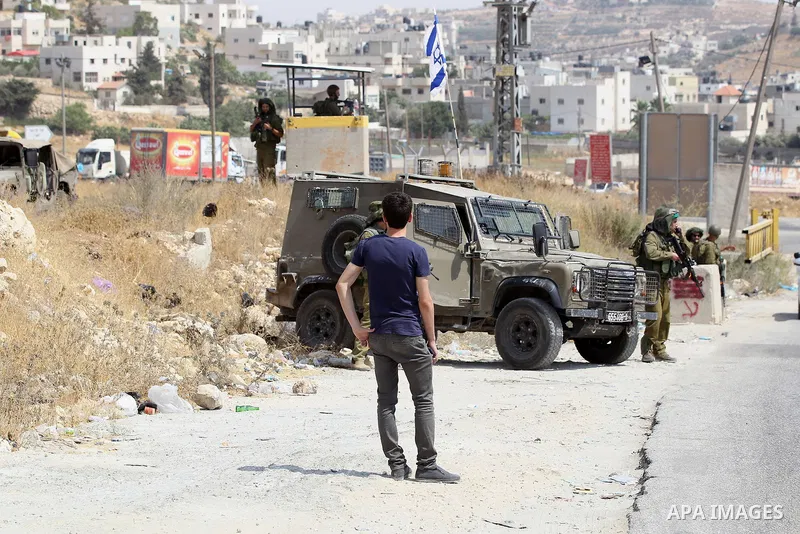 An Israeli soldier searches a Palestinian man at a temporary checkpoint near the West Bank town of Dura, south of Hebron , 24 July 2017. Photo by Wisam Hashlamoun
