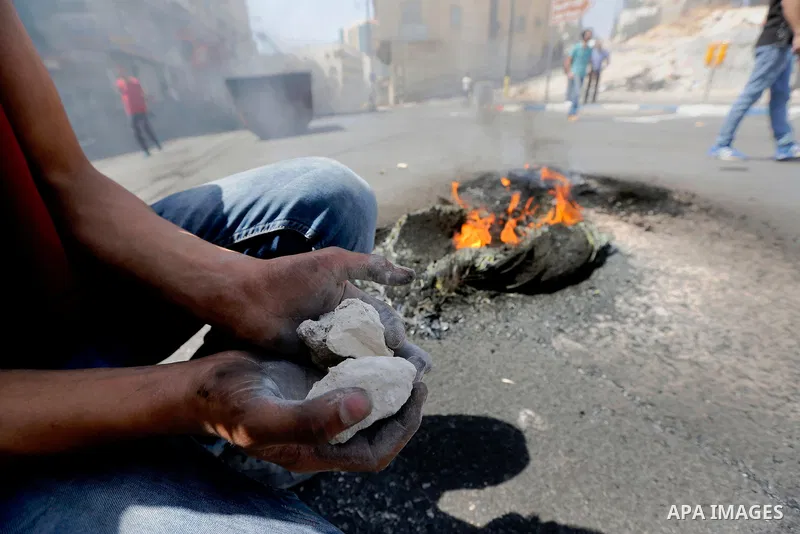 Palestinian protesters burn a tyre during clashes between demonstrators and security forces in the city of Hebron in the Israeli-occupied West Bank, on July 28, 2017, as protests erupt in support of the Al-Aqsa mosque co...