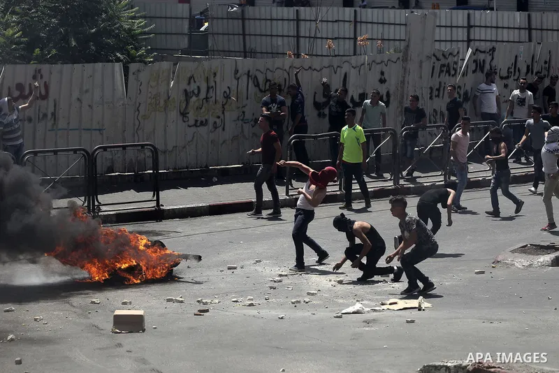Palestinian protesters burn a tyre during clashes between demonstrators and security forces in the city of Hebron in the Israeli-occupied West Bank, on July 28, 2017, as protests erupt in support of the Al-Aqsa mosque co...