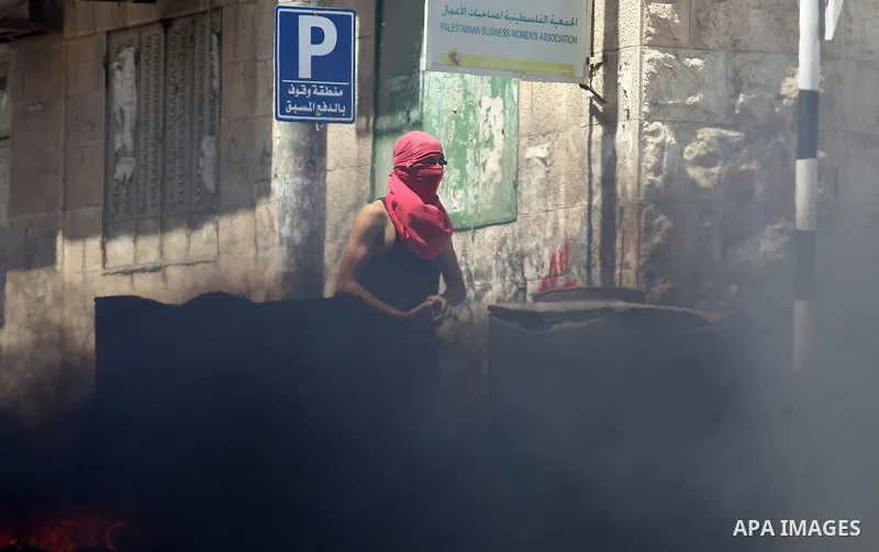 Palestinian protesters burn a tyre during clashes between demonstrators and security forces in the city of Hebron in the Israeli-occupied West Bank, on July 28, 2017, as protests erupt in support of the Al-Aqsa mosque co...