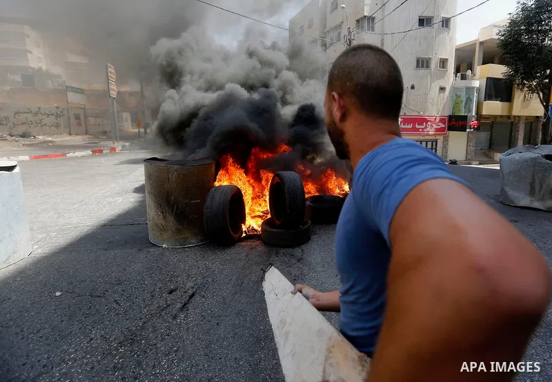 Palestinian protesters burn a tyre during clashes between demonstrators and security forces in the city of Hebron in the Israeli-occupied West Bank, on July 28, 2017, as protests erupt in support of the Al-Aqsa mosque co...