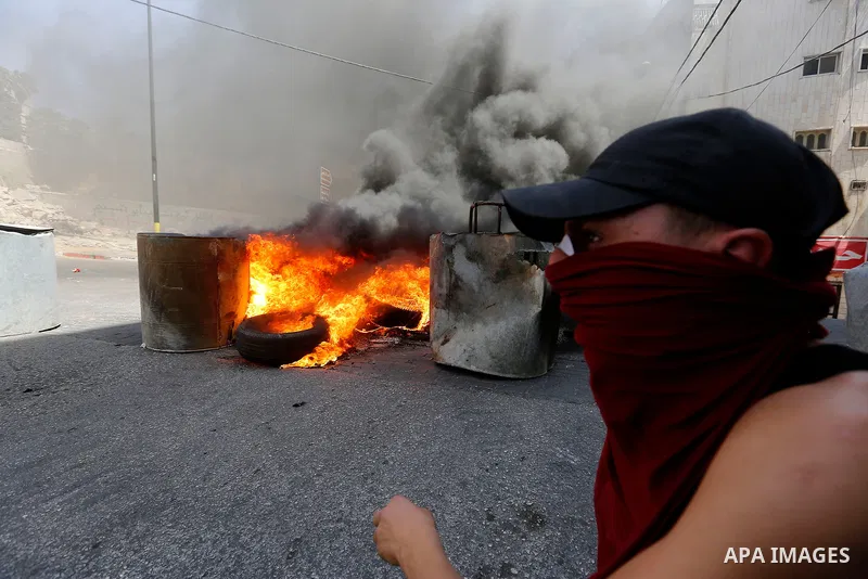 Palestinian protesters burn a tyre during clashes between demonstrators and security forces in the city of Hebron in the Israeli-occupied West Bank, on July 28, 2017, as protests erupt in support of the Al-Aqsa mosque co...