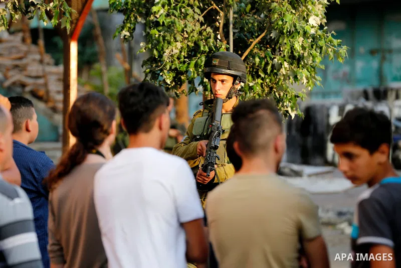 Israeli soldier stand guard while Ultra-Orthodox Jewish men under the protection of the soldiers visit a sacred Jewish site in the occupied West Bank city of Hebron, 01 August 2017. Photo by Wisam Hashlamoun