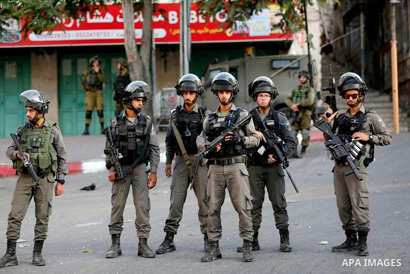 Israeli soldier stand guard while Ultra-Orthodox Jewish men under the protection of the soldiers visit a sacred Jewish site in the occupied West Bank city of Hebron, 01 August 2017. Photo by Wisam Hashlamoun