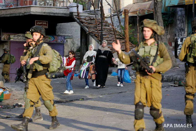 Israeli soldier stand guard while Ultra-Orthodox Jewish men under the protection of the soldiers visit a sacred Jewish site in the occupied West Bank city of Hebron, 01 August 2017. Photo by Wisam Hashlamoun