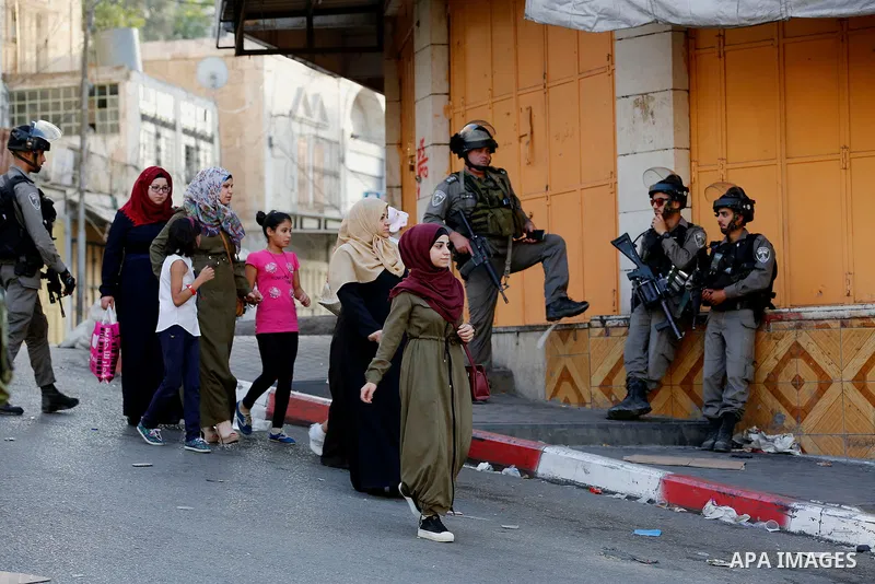 Israeli soldier stand guard while Ultra-Orthodox Jewish men under the protection of the soldiers visit a sacred Jewish site in the occupied West Bank city of Hebron, 01 August 2017. Photo by Wisam Hashlamoun