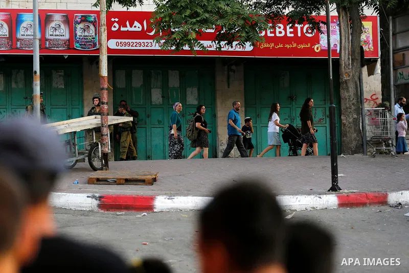 Israeli soldier stand guard while Ultra-Orthodox Jewish men under the protection of the soldiers visit a sacred Jewish site in the occupied West Bank city of Hebron, 01 August 2017. Photo by Wisam Hashlamoun