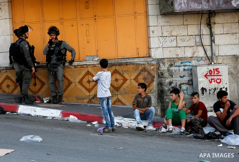 Israeli soldier stand guard while Ultra-Orthodox Jewish men under the protection of the soldiers visit a sacred Jewish site in the occupied West Bank city of Hebron, 01 August 2017. Photo by Wisam Hashlamoun