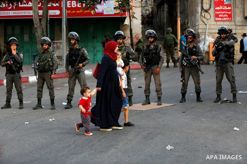 Israeli soldier stand guard while Ultra-Orthodox Jewish men under the protection of the soldiers visit a sacred Jewish site in the occupied West Bank city of Hebron, 01 August 2017. Photo by Wisam Hashlamoun