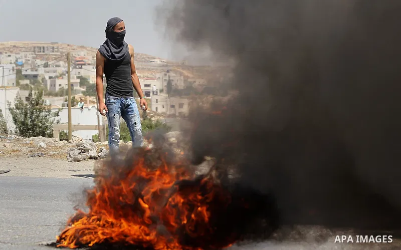 Palestinian protesters burn a tyre during a protest against building a new Israeli military tower in the West Bank town of Dura, south of Hebron August 4, 2017. Photo by Wisam Hashlamoun