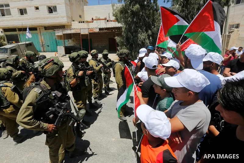 Palestinian protesters shout in front of Israeli soldiers during a protest against building a new Israeli military tower in the West Bank town of Dura, south of Hebron August 4, 2017. Photo by Wisam Hashlamoun