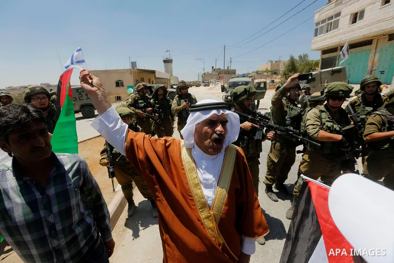 Palestinian protesters shout in front of Israeli soldiers during a protest against building a new Israeli military tower in the West Bank town of Dura, south of Hebron August 4, 2017. Photo by Wisam Hashlamoun