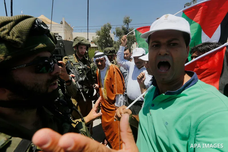 Palestinian protesters shout in front of Israeli soldiers during a protest against building a new Israeli military tower in the West Bank town of Dura, south of Hebron August 4, 2017. Photo by Wisam Hashlamoun