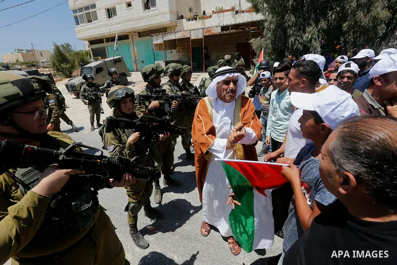 Palestinian protesters shout in front of Israeli soldiers during a protest against building a new Israeli military tower in the West Bank town of Dura, south of Hebron August 4, 2017. Photo by Wisam Hashlamoun