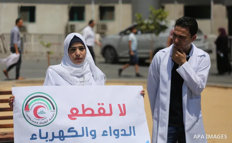 Palestinian doctors hold placards during a protest against a power cut and the Israeli blockade of the Gaza Strip, at al-Shifa Hospital in Gaza city on August 8, 2017. Photo by Mohammed Asad