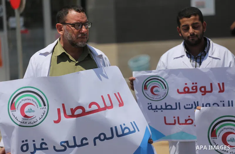 Palestinian doctors hold placards during a protest against a power cut and the Israeli blockade of the Gaza Strip, at al-Shifa Hospital in Gaza city on August 8, 2017. Photo by Mohammed Asad