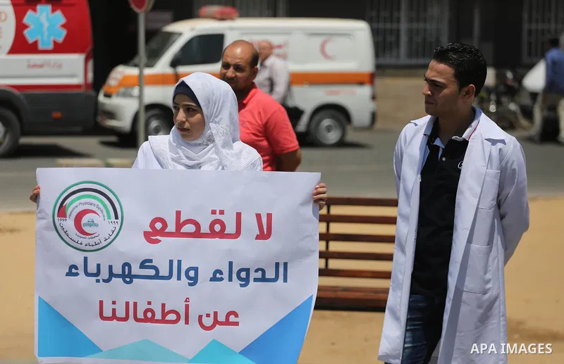 Palestinian doctors hold placards during a protest against a power cut and the Israeli blockade of the Gaza Strip, at al-Shifa Hospital in Gaza city on August 8, 2017. Photo by Mohammed Asad