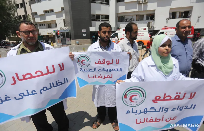 Palestinian doctors hold placards during a protest against a power cut and the Israeli blockade of the Gaza Strip, at al-Shifa Hospital in Gaza city on August 8, 2017. Photo by Mohammed Asad