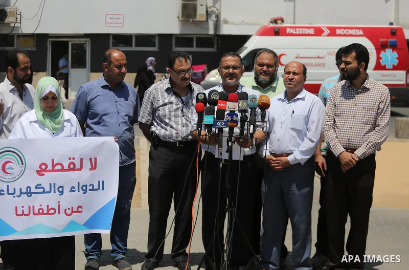 Palestinian doctors hold placards during a protest against a power cut and the Israeli blockade of the Gaza Strip, at al-Shifa Hospital in Gaza city on August 8, 2017. Photo by Mohammed Asad