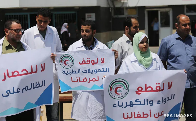 Palestinian doctors hold placards during a protest against a power cut and the Israeli blockade of the Gaza Strip, at al-Shifa Hospital in Gaza city on August 8, 2017. Photo by Mohammed Asad