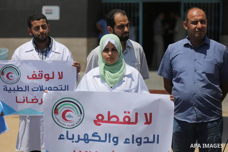 Palestinian doctors hold placards during a protest against a power cut and the Israeli blockade of the Gaza Strip, at al-Shifa Hospital in Gaza city on August 8, 2017. Photo by Mohammed Asad