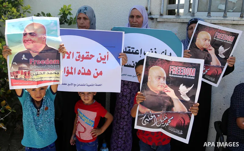 Palestinians hold posters of Mohammad El Halabi, World Vision's manager of operations in Gaza who was accused by Israel of funnelling millions of dollars in aid money to Hamas, during a protest in solidarity with El Hala...