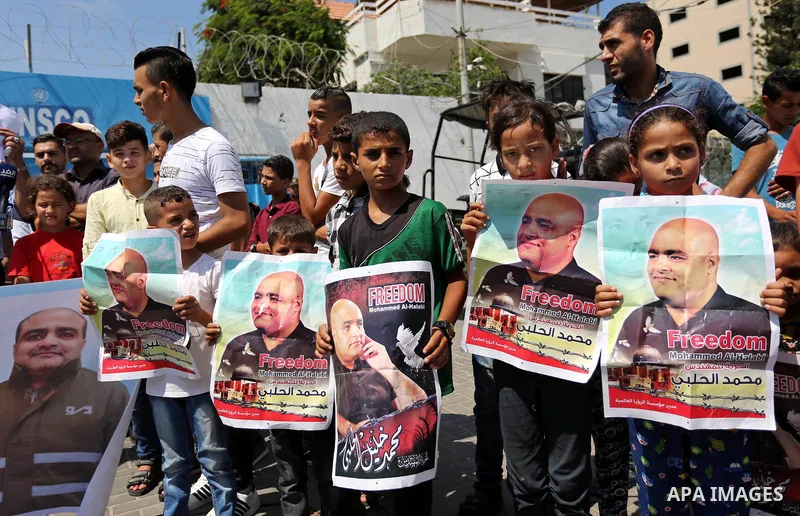 Palestinians hold posters of Mohammad El Halabi, World Vision's manager of operations in Gaza who was accused by Israel of funnelling millions of dollars in aid money to Hamas, during a protest in solidarity with El Hala...
