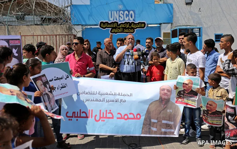 Palestinians hold posters of Mohammad El Halabi, World Vision's manager of operations in Gaza who was accused by Israel of funnelling millions of dollars in aid money to Hamas, during a protest in solidarity with El Hala...