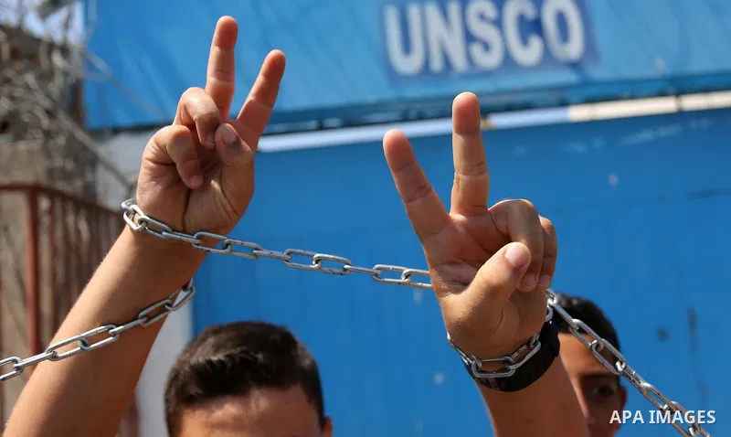 Palestinians hold posters of Mohammad El Halabi, World Vision's manager of operations in Gaza who was accused by Israel of funnelling millions of dollars in aid money to Hamas, during a protest in solidarity with El Hala...