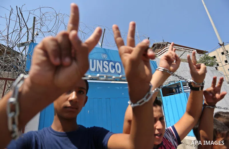 Palestinians hold posters of Mohammad El Halabi, World Vision's manager of operations in Gaza who was accused by Israel of funnelling millions of dollars in aid money to Hamas, during a protest in solidarity with El Hala...