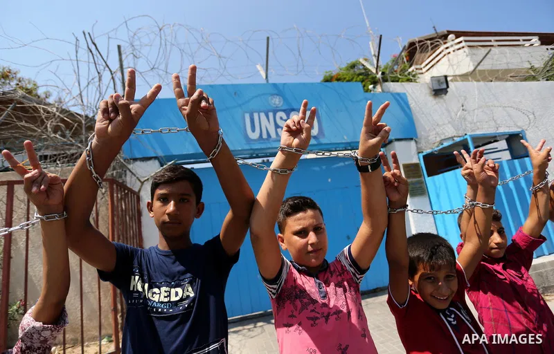 Palestinians hold posters of Mohammad El Halabi, World Vision's manager of operations in Gaza who was accused by Israel of funnelling millions of dollars in aid money to Hamas, during a protest in solidarity with El Hala...