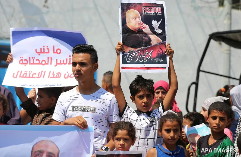 Palestinians hold posters of Mohammad El Halabi, World Vision's manager of operations in Gaza who was accused by Israel of funnelling millions of dollars in aid money to Hamas, during a protest in solidarity with El Hala...