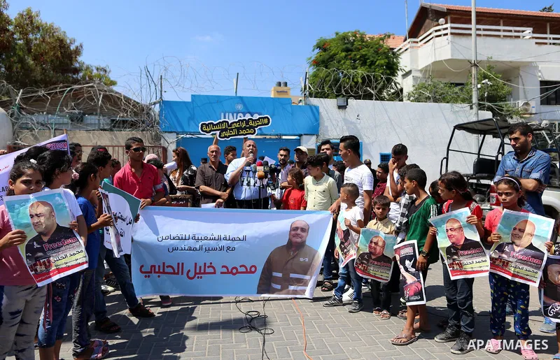 Palestinians hold posters of Mohammad El Halabi, World Vision's manager of operations in Gaza who was accused by Israel of funnelling millions of dollars in aid money to Hamas, during a protest in solidarity with El Hala...
