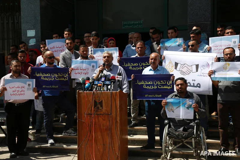 Palestinian journalists hold banners reading in Arabic ''Being a journalsit is not a crime'' and ''No to closing Al-Jazeera channel'' during a sit-in in solidarity with the al-Jazeera Arab satellite news broadcaster, in...